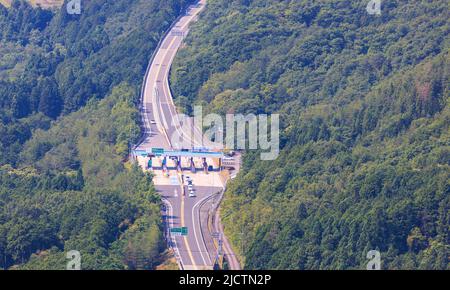 Luftaufnahme von Autos, die durch die Mautstelle auf der Autobahn im Wald fahren Stockfoto