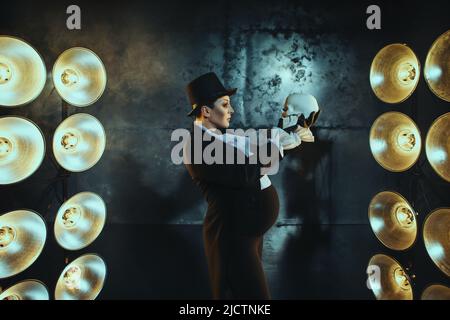 Schwanger Mädchen auf dem Bild eines dicken Mannes vor dem Hintergrund von Lampen in der Dunkelheit Stockfoto