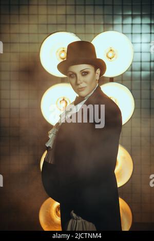 Schwanger Mädchen auf dem Bild eines dicken Mannes vor dem Hintergrund von Lampen in der Dunkelheit Stockfoto