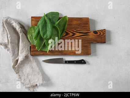 Große saftige Spinatblätter auf einem Schneidebrett, Nahaufnahme Stockfoto