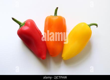 Ein Trio aus kleinen bunten Paprika auf weißem Hintergrund Stockfoto