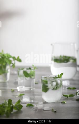 Glas kaltes Wasser mit frischen Minzblättern und Eiswürfeln Stockfoto