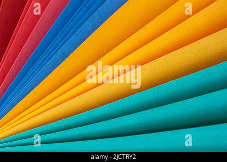 Mehrfarbige Blätter aus Papier, die wie ein Regenbogenventilator aus der Nähe gefaltet sind. Abstrakter, farbenfroher Hintergrund Stockfoto
