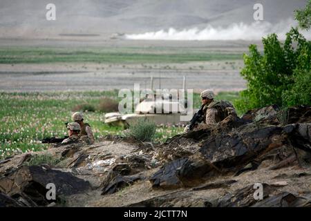 US-Marineinfanteristen mit 1. Bataillons, 8. Marine Regiment (1/8), Regimental Combat Team 6, sichern sich eine Hügelseite auf Patrouille, da M1 Abrams-Panzer Sicherheit bieten Stockfoto