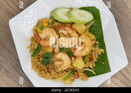 Blick von oben auf Ananas gebratener Reisplatte mit großen Garnelen, großzügigen Gurkenscheiben und verzehrfertig. Stockfoto