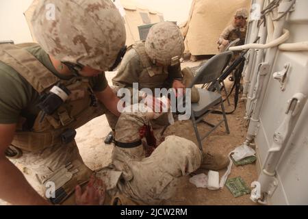 US-Marineinfanteristen und Marinesoldaten leisten erste Hilfe für eine Waffe, die Marine während eines Feuergefechtes in Kajaki, Afghanistan, verletzt hat. Stockfoto