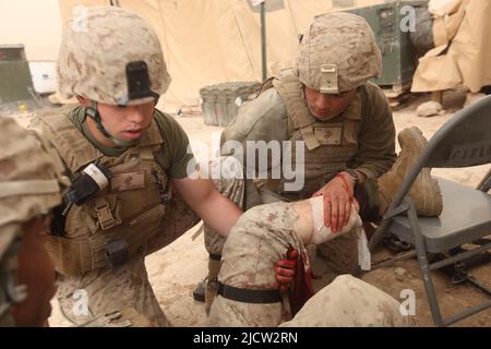 US-Marineinfanteristen und Marinesoldaten leisten erste Hilfe für eine Waffe, die Marine während eines Feuergefechtes in Kajaki, Afghanistan, verletzt hat. Stockfoto