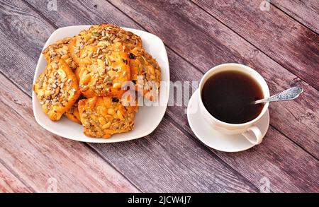 Ein Stapel von Shortbread-Keksen mit Sesam und Erdnüssen auf einem Teller und einer Tasse Tee. Draufsicht, flach liegend. Stockfoto