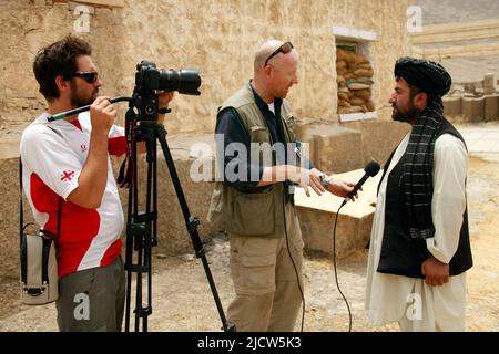 Bernard Smith, Mitte, Reporter, und Ben Foley, links, Kameramann mit Al Jazeera English News Channel interviewt einen afghanischen Einheimischen in Kajaki, Hel Stockfoto