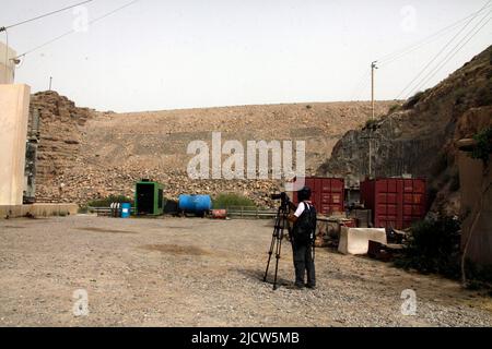 Ben Foley, Kameramann, mit Al Jazeera English News Channel filmt die Außenseite des Kajaki-Staudamms mit dem Damm direkt rechts von ihm Stockfoto