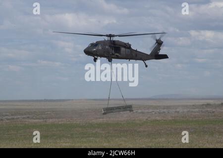 Soldaten des 5. Bataillons, des 113. Field Artillery Regiments, North Carolina National Guard, führen während des Western Strike 22 im Orchard Combat Training Center, Idaho, Sling-load-Operationen in Verbindung mit Piloten des 2. General Aviation Support Bataillons, des 211. Aviation Regiment, Utah National Guard, durch. WESTERN Strike 22 ist eine exportierbare Kampftrainingsübung, die von der 65. Field Artillery Brigade, Utah National Guard, geleitet wird und Soldaten der Nationalgarde ähnlich wie in einem Kampftrainingszentrum unterbringt und die Bereitschaft und Letalität der teilnehmenden Einheit erhöhen soll. ( Stockfoto