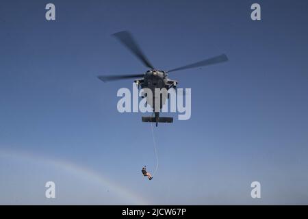 GOLF VON ADEN (9. Juni 2022) ein Helikopter der MH-60s Sea Hawk, der an die „Sea Knights“ des Hubschrauber-Seekampfgeschwaders (HSC 22) und Seeleute des Küstenkampfschiffs USS Sioux City (LCS 11) angeschlossen ist, führt im Golf von Aden am 9. Juni Such- und Rettungstrainings durch. Sioux City wird im Einsatzgebiet der US-Flotte für 5. eingesetzt, um die Sicherheit und Stabilität der Seefahrt in der Region des Nahen Ostens zu gewährleisten. (USA Navy Foto von Mass Communication Specialist 3. Klasse Nichola A. Russell) Stockfoto