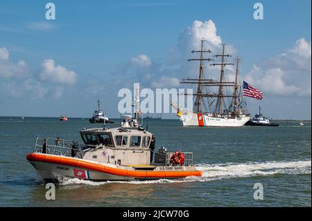 Eine Küstenwache Galveston 45-Fuß-Boot-Medium bietet Sicherheit, während die US-Küstenwache Cutter Barque Eagle den Galveston-Kanal in Richtung Pier 21 in Galveston, Texas, durchfährt, 10. Juni 2022. Der Eagle, der an der Coast Guard Academy in New London, Connecticut, untergebracht ist, wird als Trainingsplattform für zukünftige Küstenwache-Offiziere genutzt und besuchte Galveston, Texas, zum ersten Mal seit 1972. (USA Foto der Küstenwache von Petty Officer, Klasse 2., Ryan Dickinson) Stockfoto