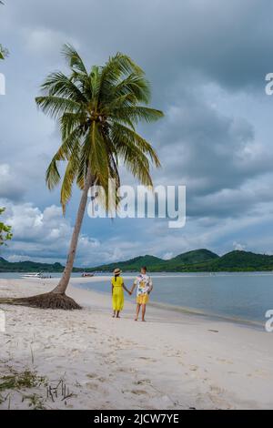 Ein paar Männer und Frauen gehen am Strand auf der Insel Koh Yao Yai Thailand, Strand mit weißem Sand und Palmen. Stockfoto