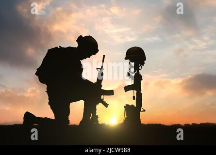 3D Illustration eines Militärs, der bei Sonnenuntergang vor dem gefallenen Soldatengrab kniet Stockfoto