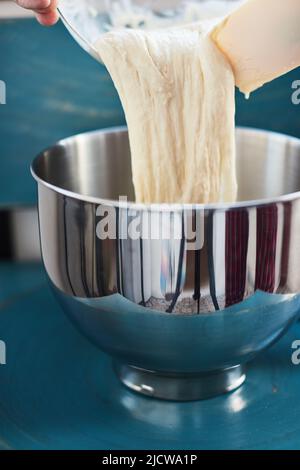 Der Prozess der Herstellung von Weizenbrot zu Hause. Sauerteig für Brot vor dem Kneten. Das Konzept der gesunden hausgemachten Speisen. Vertikales Foto. Stockfoto