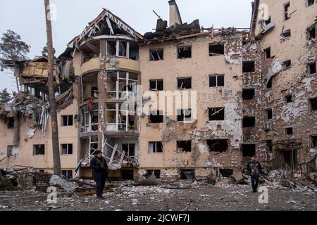 IRPIN, UKRAINE 03. März. Mitglieder der Territorialen Verteidigungskräfte kommen an einem Wohngebäude vorbei, das durch den jüngsten Beschuss zerstört wurde, während die russische Invasion in der Ukraine am 03. März 2022 in Irpin, Ukraine, fortgesetzt wird. Russland begann am 24. Februar 2022 eine militärische Invasion der Ukraine, nachdem das russische parlament Verträge mit zwei abtrünnigen Regionen in der Ostukraine gebilligt hatte. Es ist der größte militärische Konflikt in Europa seit dem Zweiten Weltkrieg Stockfoto