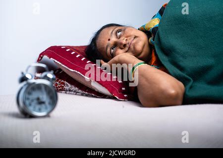 Eine Frau im Alter zwischen zwei Jahren, die nachts im Schlafzimmer an Schlaflosigkeit leidet - ein Konzept von Alptraum, Schlaflosigkeit und Traurigkeit. Stockfoto
