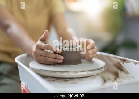 Handwerker Hände machen Töpferschale. Frau, die am Töpferrad arbeitet. Der Familienladen formt den Topf aus Lehm. Stockfoto