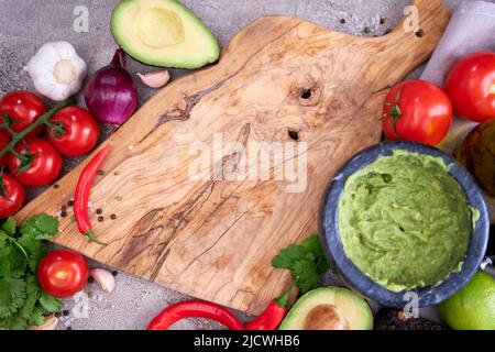 Making Guacamole - zerdrückte Avocado in Marmormörtel und Zutaten Stockfoto