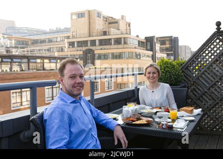 Pärchen frühstücken auf einer Dachterrasse in der Großstadt Stockfoto