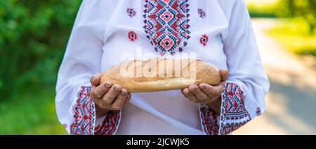 Großmutter mit ukrainischem Brot in den Händen. Selektiver Fokus. Stockfoto
