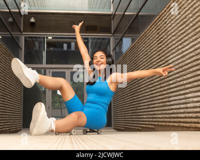 Seitenansicht einer jungen, schlanken Frau in Sportkleidung, die auf einer Matte sitzt und die Arme streckt, während sie zu Hause Yoga praktiziert Stockfoto