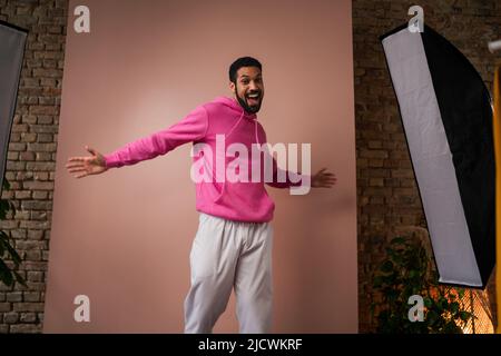 Portrait eines jungen afroamerikanischen Mannes in pinkem Hoodie auf beigem Hintergrund. Stockfoto