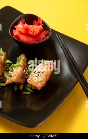 Gyoza oder Jiaozi Asiatische frittierte Knödel mit Sojasauce und grüne Zwiebeln auf schwarzem Beton, Draufsicht Stockfoto