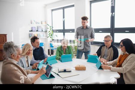 Gruppe von Senioren, die mit dem Lehrer an DER IT-Klasse im Gemeindezentrum teilnehmen Stockfoto