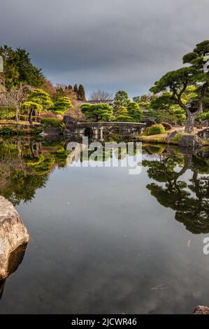 Himeji, Japan - 6. Januar 2020. Außenaufnahme eines japanischen Gartens mit einem Teich mit bunten Fischen in der Nähe des Schlosses Himeji. Himeji Schloss in einem der letzten verbliebenen authentischen Schlösser in Japan und eine beliebte Touristenattraktion. Stockfoto