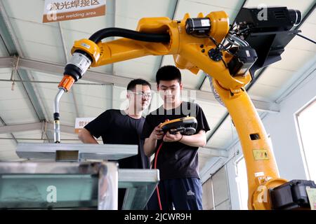 BINZHOU, CHINA - 16. JUNI 2022 - zwei Techniker debuggen auf der Black Dot Electronics Technology ein Auftragsprodukt eines neu entwickelten Industrieroboters Stockfoto