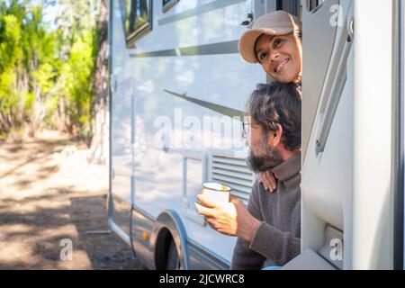 Junge Paar von Touristen mit Wohnmobil an der Tür sitzen genießen Natur im Freien Freizeit Gefühl. Reisen Menschen und Berge Ziel c Stockfoto