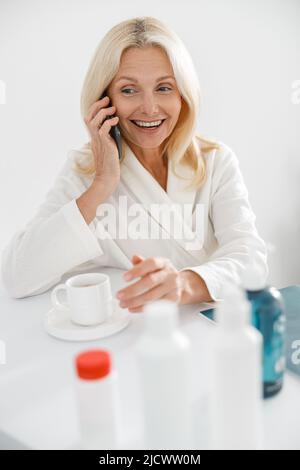 Portrait der kaukasischen blonden Frau, die im weißen Wellness-Center auf dem Mobiltelefon anruft Stockfoto