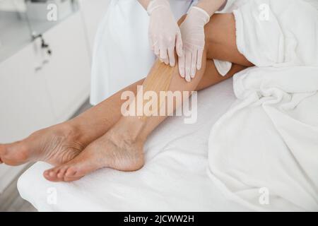 Frau Client mit Haarentfernung Verfahren auf Bein mit Zuckerpaste im Schönheitssalon Stockfoto