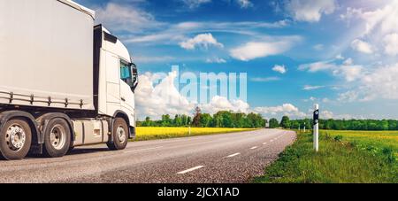 LKW bewegt sich an sonnigen Tagen im Frühjahr auf der asphaltierten Landstraße Stockfoto