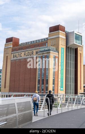 Zwei junge Männer gehen auf der Millennium Bridge, Newcastle upon Tyne, Großbritannien, in Richtung BALTIC Art Gallery in Gateshead. Stockfoto