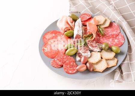 Wurstplatte mit verschiedenen Wurstsorten - Salami, Bresaola, Proscuitto serviert mit Oliven und Crackern. Menühintergrund. Traditionelles italien Stockfoto