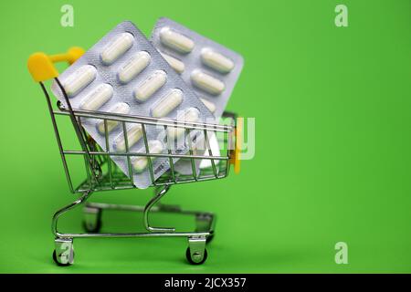 Warenkorb mit medizinischen Pillen auf grünem Hintergrund Stockfoto