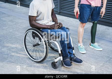 Beschnittene Ansicht von multiethnischen Freunden mit Behinderung, die Spaß im Freien haben - Fokus auf prothetische Beine Stockfoto