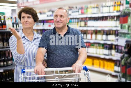 Das ältere Paar kauft Wein in der Alkoholabteilung eines Supermarkts Stockfoto