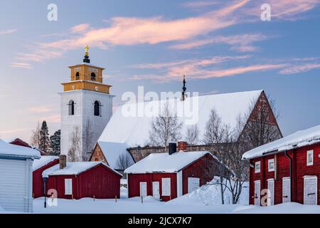 Alte Kirche und malerische Gebäude mit Schnee bei Sonnenuntergang in Gammelstad Altstadt, UNESCO-Weltkulturerbe, Lulea, Schweden, Skandinavien bedeckt Stockfoto