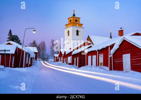 Autospuren Lichter auf der vereisten Straße, die die mittelalterliche, schneebedeckte Kirchenstadt Gammelstad überquert, UNESCO-Weltkulturerbe, Lulea, Schweden Stockfoto