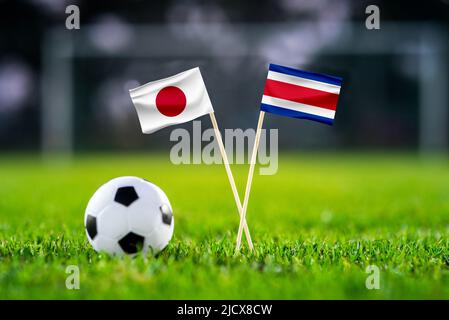 Oktober 2022: Japan gegen Costa Rica, Ahmed bin Ali Stadium, Fußballmatchtapete, Handgefertigte Nationalflaggen und Fußball auf grünem Gras. Fußball s Stockfoto