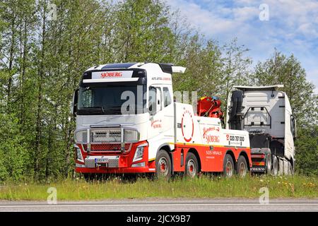 Volvo FH Schwerlast-Bergungsfahrzeug aus Sjöberg Oy Schleppen eines Sattelschlepper auf Highway 2 Kreuzung im Sommer. Forssa, Finnland. 10. Juni 2022. Stockfoto