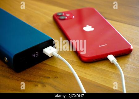 30 April 2021 Eskisehir Türkei. Rotes iphone 11 wird von Powerbank auf Holztisch geladen Stockfoto