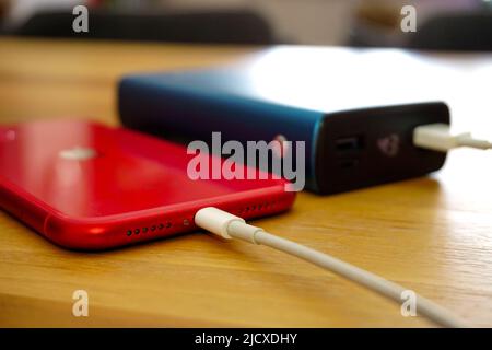 30 April 2021 Eskisehir Türkei. Rotes iphone 11 wird von Powerbank auf Holztisch geladen Stockfoto