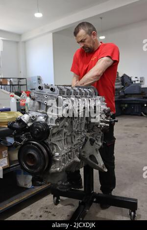 Mechaniker, der am Dieselmotor in der Motorreparatur-Werkstatt arbeitet Stockfoto