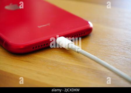 30 April 2021 Eskisehir Türkei. Rotes iphone 11 wird von Powerbank auf Holztisch geladen Stockfoto