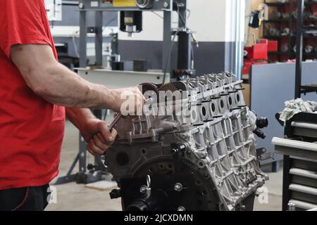 Mechaniker, der am Dieselmotor in der Motorreparatur-Werkstatt arbeitet Stockfoto